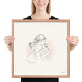 Room in My Heart, a fine-line drawing of a mother holding her baby girl with a little sister at her side, Beloved print by Jamie Lawrence in a Red Oak frame, held to show scale